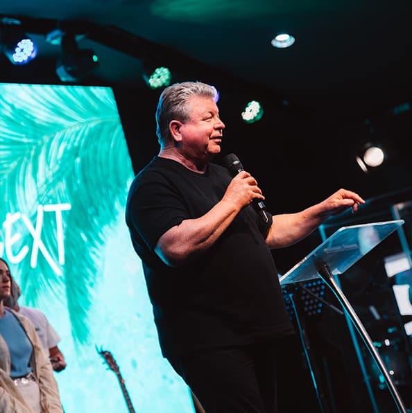 Senior pastor preaching with a microphone on stage during a City on a Hill Church service