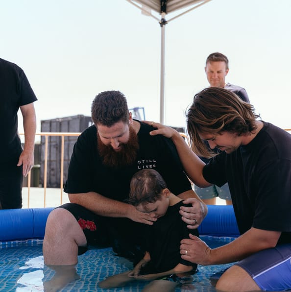 Child being baptised by church leaders in a baptism pool at City on a Hill Church